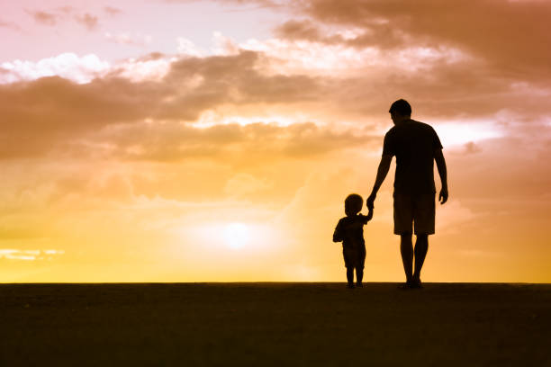 Loving father walking side by side with son holding hands